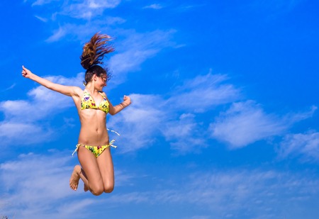 Attractive Girl in Bikini Jumping on the Beach Having Fun, Summer vacation holiday Lifestyle. Happy women jumping freedom on sand.の写真素材