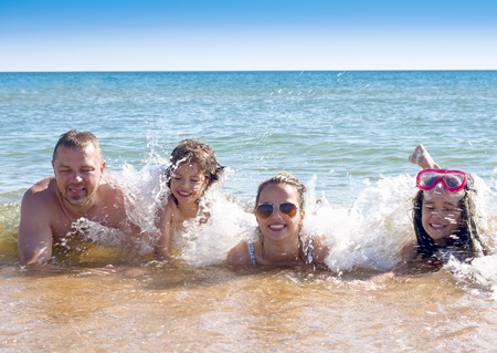 Family On Summer Beach Vacation lying in the water and enjoying each other's company.Happy family vacation conceptの写真素材