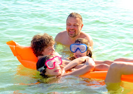 happy family with children is swimming and having fun in the sea on an inflatable mattress. happy...