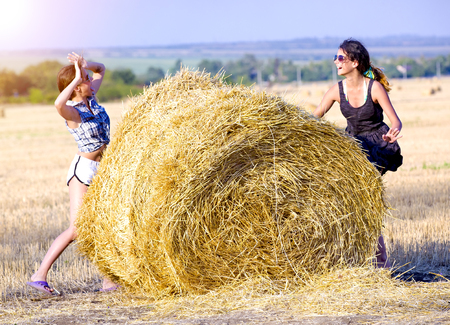 Girls playing with the round wheat dried bales outdoor summerの写真素材
