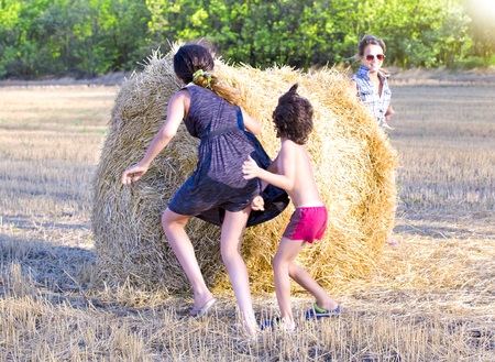 Children on haystacks in the sunlight running, playing enjoying nature. People play hide and seek. Children environment conceptの写真素材