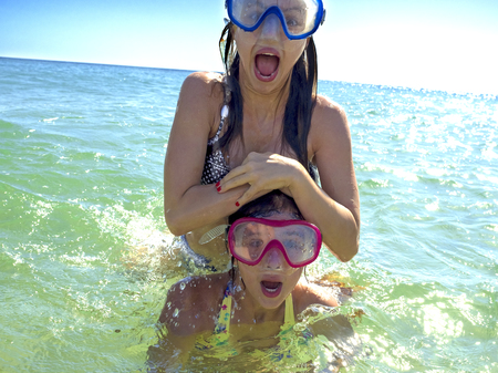 Young sisters portrait having fun together at the sea in summer time. Lifestyle concept.の写真素材