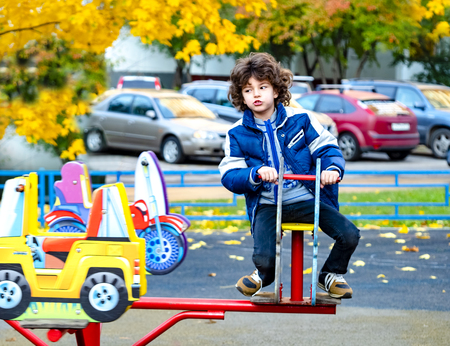 Little boy having fun with carousel on outdoor playground. Spring or autumn active sport leisure for kids. Kindergarten or school yard. Toddler child activityの写真素材