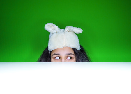 The girl with his ears on his head looks out of the tableの写真素材