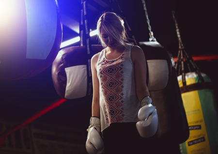 woman wearing boxing gloves shot in boxing hall low key lighting.light blurの写真素材