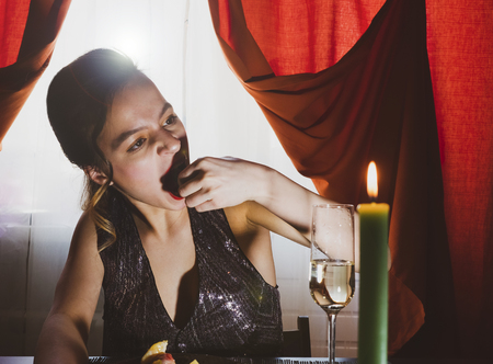 A beautiful drunk girl in a restaurant eating dessert. Stunning girl are sitting in a cafe and drinking champagne.Vintage style. Selective focus.Gluttony concept.Selective focus.の写真素材
