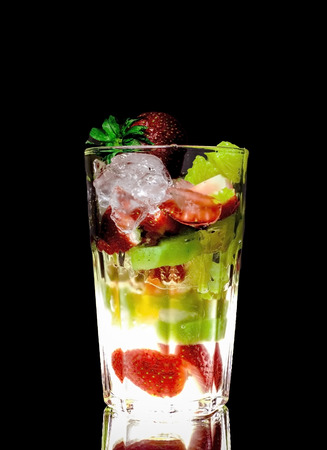 Dessert layered in a transparent glass, mineral water, orange, kiwi, nuts on a black background. The concept of healthy, proper and simple Healthy foodの写真素材