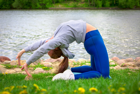 young girl goes in for sports in nature. healthy lifestyle.flaxible child doing joga poses bridge streching in the natureの写真素材
