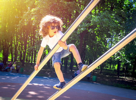 Boy is climbing on iron pipes on the playgroundの写真素材