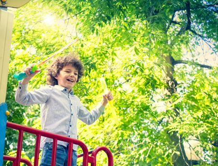 Boy blowing the soap bubbles in the park on a sunny dayの写真素材