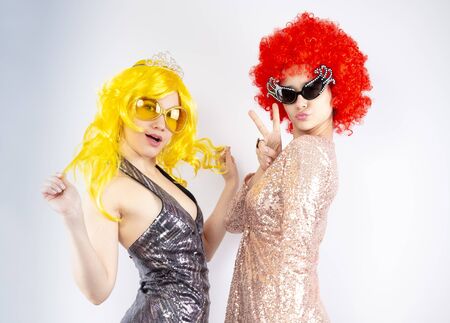 Two glamorous and beautiful girls in bright clothes, looking at the camera with astonishment. Girlfriends posing while preparing for a Christmas party. Carnival fun concept.の写真素材