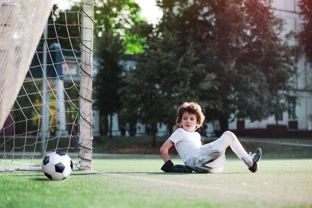 Children's soccer football - a match of young children on the football field. Young goalie. Kids - soccer champion. Boy goalkeeper in football sportswear on stadium with ball. Sport concept.の写真素材