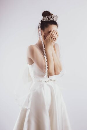 Young bride crying isolated on gray backgroundの写真素材
