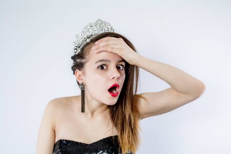 Young beautiful girl wearing black evening gown with open shoulders standing over isolated gray background Crazy and scared with hands on head, afraid and surprised of shock with open mouth. Isolateの写真素材