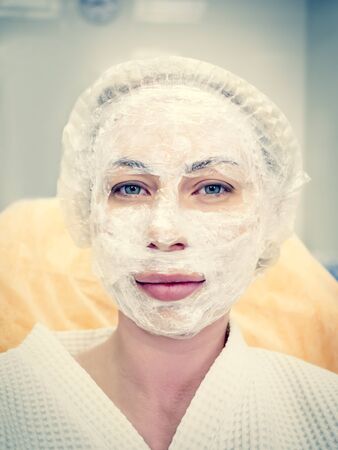 Cosmetic mask on the face of a woman in the spa salon. Woman in mask on face in spa beauty salonの写真素材