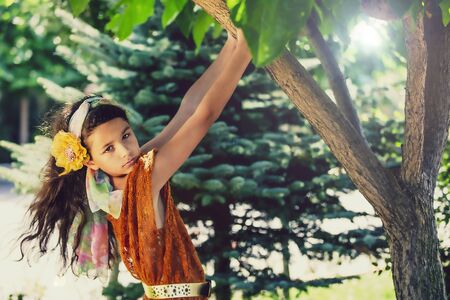 Young beautiful stylish girl in red mesh summer tunic and swimsuit walking and posing between trees. hanging on tree and having fun in summer park. Summer concept.の写真素材