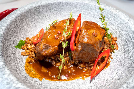 Stewed beef cheeks with spelled in a marble gray plate on a green tablecloth. Decor. Selective focus. Super short focusの写真素材