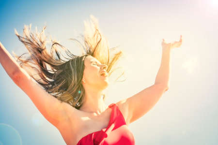 A young slender, beautiful European middle-aged woman flew to rest, mature pants in a red swimsuit against the sky. The wind develops her long dark hairの写真素材