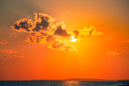 The sun with dark clouds in the orange red sky, the power of nature. Setting sun aa cloudy sky.の写真素材