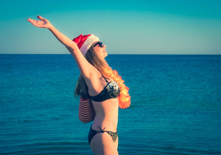 Beautiful young woman in Santa Hut, Hawaii accessory and bikini on beach. Christmas vacationPretty...