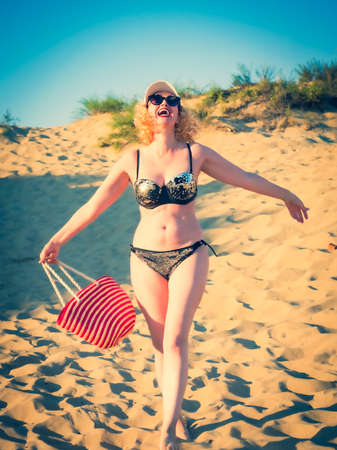 Pretty middle aged woman in black shiny swimsuit enjoying sand tropical beach. Travel and beach vacation conceptの写真素材