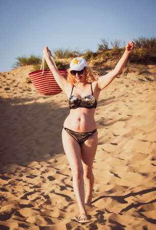 Pretty middle aged woman in black shiny swimsuit enjoying sand tropical beach. Travel and beach vacation conceptの写真素材