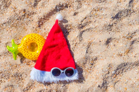 Santa Claus hat with masquerade goggles on sea coast. Christmas vacation On Sunny Dayの写真素材
