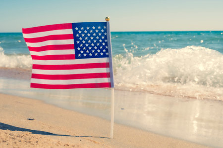 USA patriotic background with American flag on a sandy beach.