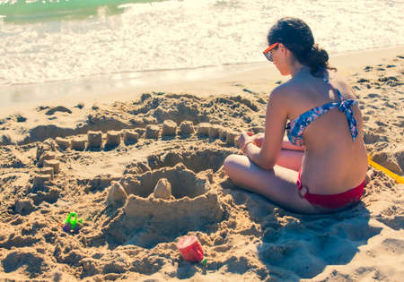 Happy teenage kids playing with sand on the seasideの写真素材
