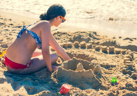Happy teenage kids playing with sand on the seasideの写真素材