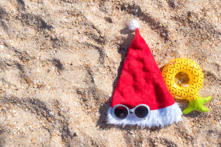 Santa Claus hat with masquerade goggles on sea coast. Christmas vacation On Sunny Day