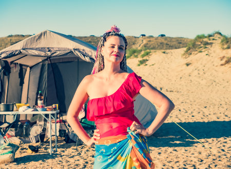 Beautiful caucasian woman with african braids enjoying the freedom in free camping at the beach and tent alternative people travel conceptの写真素材