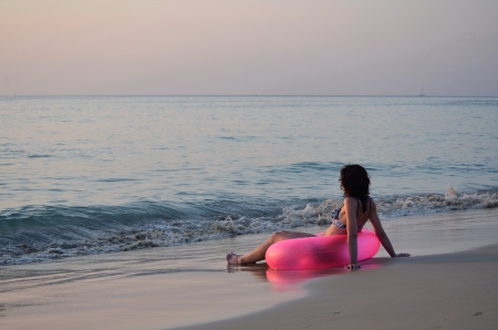 Women with pink ring at the ocean on sunriseの写真素材