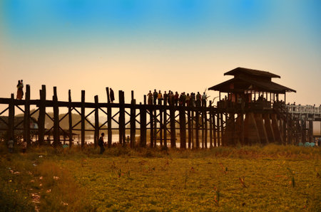 Amarapura, Myanmar - 14 March 2015: People walking on the wooden bridge of U Bein on river...
