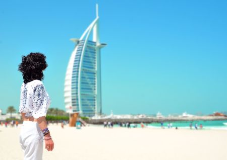 DUBAI, UNITED ARAB EMIRATES - MAY 2017 : Woman in front of Burj Al Arab, famous landmarks of United Arab Emirates seen from public beach.のeditorial素材