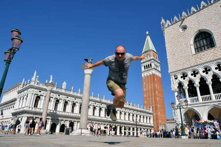 VENICE, ITALY - APRIL 19, 2021: man jump near saint mark bell tower and palace of Doge in Venice, Italyのeditorial素材