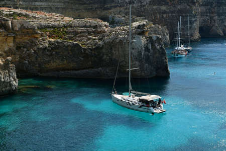 Comino island with cliffs, tourist boats and blue sea.の写真素材