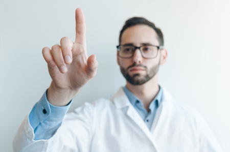 Young doctor pushing by a finger. layout for a futuristic screen medical panel. Blurredの写真素材