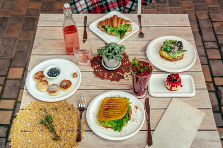 breakfast served cafe table with cheese pancakes, sandwich, croissant and drinks and menu card. Top...