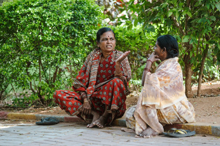 Two indian woman sit on the ground and speaks. 8 february 2018 Sai Baba Ashram Puttaparthi