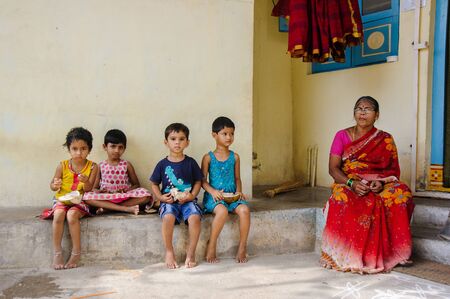 group of indian kids sits at the street and eating coconuts. 11 february 2018 Puttaparthi, Indiaのeditorial素材