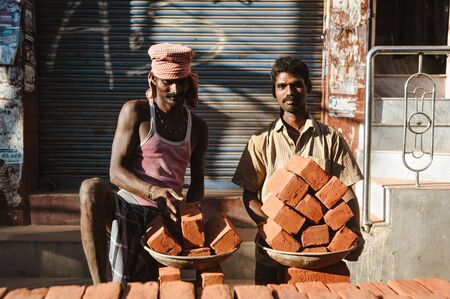 two indian workers in outdoors with plates ful of bricks, 23 february 2018 Madurai, Indiaのeditorial素材