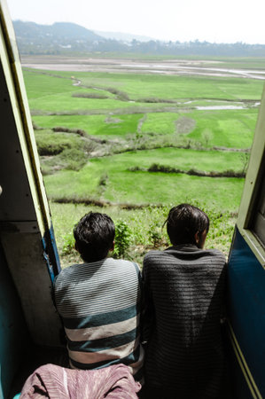 27 february 2018 Amritsar, India. two indian boys in train doors and lookint ant beautiful green...