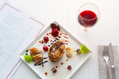 dinner or lunch with dish per one person. luxury white interior of restaurant. red wine and chicken with pearの写真素材