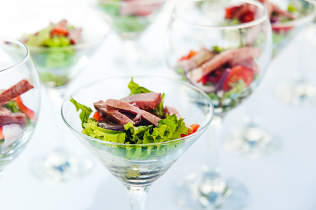 wine glasses with salad and meat snack at reception. catering snackの写真素材