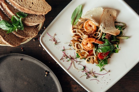 seafood salad with shrimps and squid in composition with bread at dark wooden backgroundの写真素材