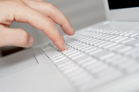 mans hand typing on white keyboard by fingers. white style workspace technics