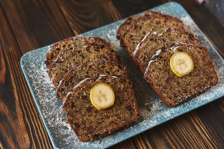 sliced homemade brown cake at blue dish decorated with two banana pieces.の写真素材