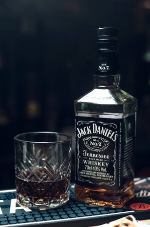 26.01.2019. Russia, Sevastopol. jack daniels bottle with half ful glass at bar counter in dark, vertical. copy space.のeditorial素材