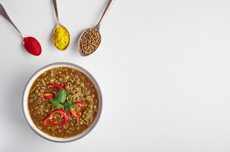 Mung Dhal decorated with red pepper slices isolated at white. Moong Dal - Indian Cuisine curry. Vegetarian dish with mung beans, zira cumin, coriander, curcuma and chili. Top view with copy spaceの写真素材